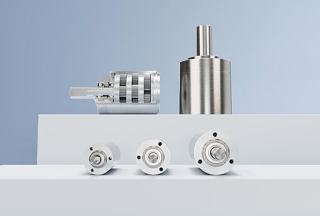 FAULHABER GPT 系列的各种行星齿轮减速器排列在灰蓝色背景前的白色台阶上。