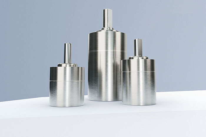 三台FAULHABER GPT系列行星齿轮减速机，排列在灰蓝色背景前的白色阶梯上。