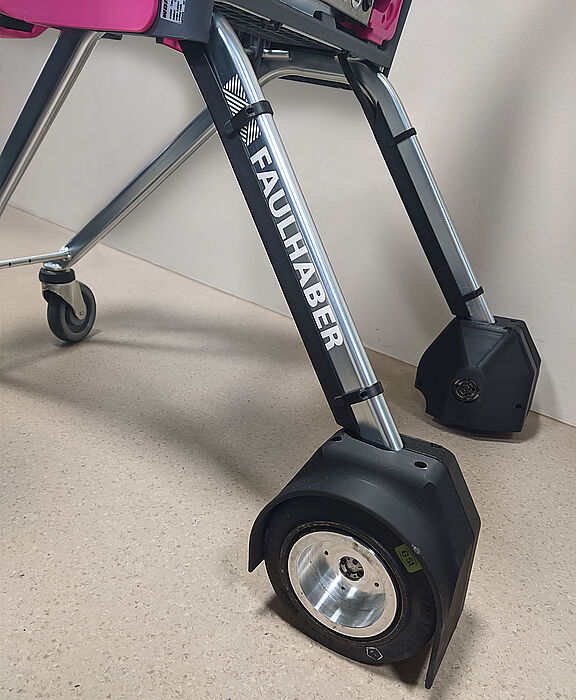 FAULHABER无刷电机应用于拉珀斯维尔应用科学大学(OST)自主购物车VIRAS项目 瑞士拉珀斯维尔 OST 应用科技大学开发的自主购物车“VIRAS”的轮子和支架特写图。图中展示了带有 FAULHABER 标志的车架和配备驱动系统的车轮。