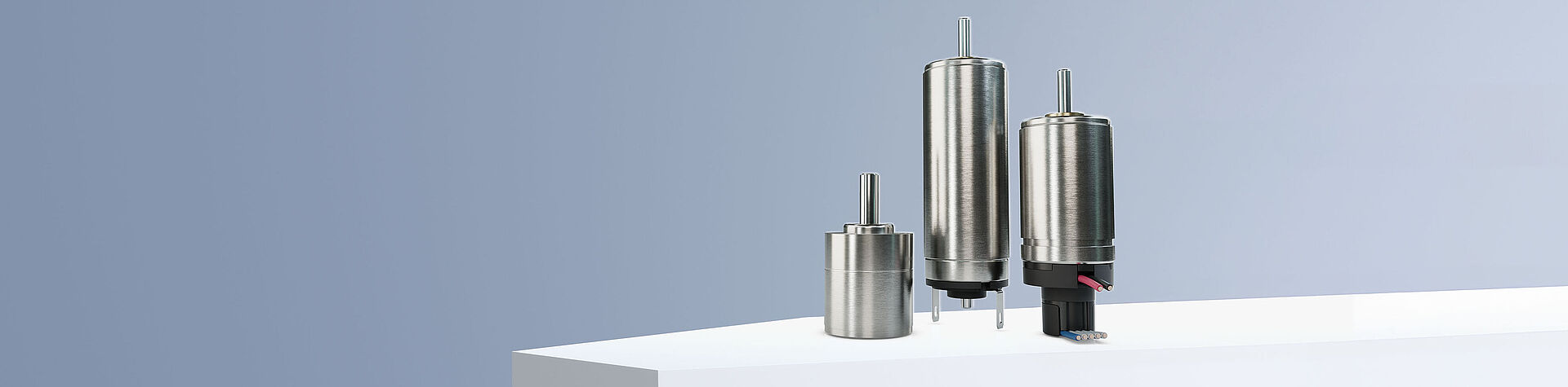 两台来自 FAULHABER SXR 和 GXR 产品系列的直流电机以及一个编码器和一个来自 GPT 产品系列的减速机排列在灰蓝色背景下的白色台阶上。