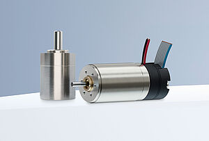 两台 FAULHABER SXR 和 GXR 系列直流电机和一个编码器，排列在灰蓝色背景下的白色平台上。