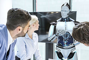 四位身着商务装的专业人士围坐在会议桌前，注视着一个在人前演示的类人机器人——象征人与技术对话的形象，用于FAULHABER商务拓展团队的访谈背景。