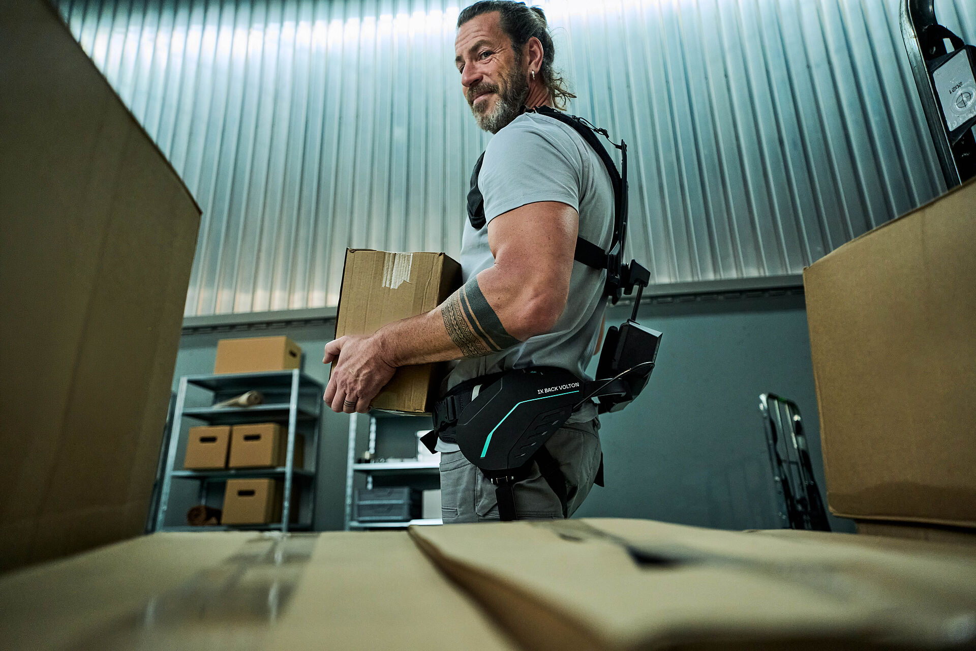 一名仓库员工在搬运箱子时佩戴 SUITX 的 IX BACK VOLTON 外骨骼，其运动辅助由集成的 FAULHABER 驱动系统实现。