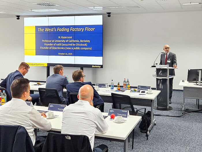FAULHABER Customer Day 2025 Keynote Humanoid Robotics Prof. Homayoon Kazerooni speaks at the podium during the FAULHABER Customer Day, addressing an audience of customers and employees. A slide from his presentation on humanoid robotics is visible on a screen in the background.