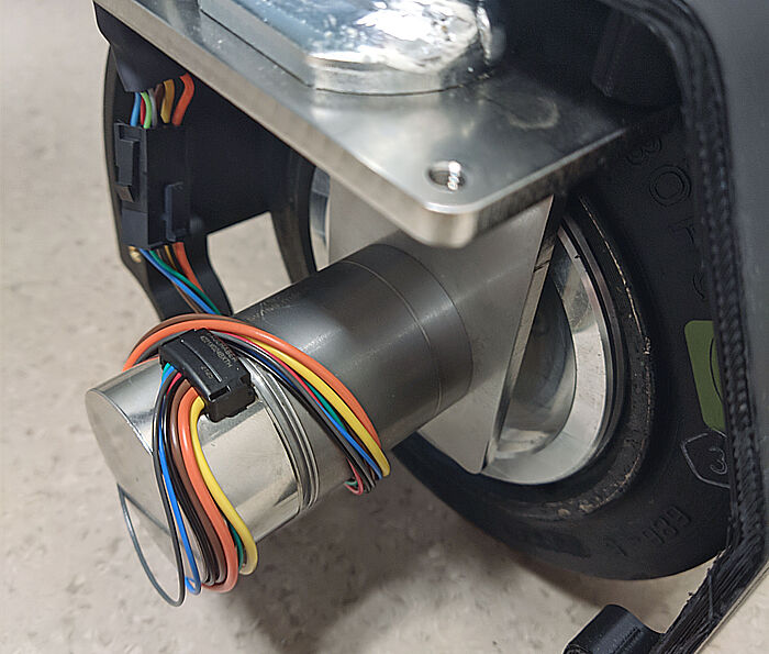 FAULHABER无刷电机应用于拉珀斯维尔应用科学大学(OST)自主购物车VIRAS项目 自动购物车“VIRAS”的车轮驱动单元特写图,该购物车由瑞士OST应用科技大学拉珀斯维尔分校开发。图中可见电机组件、彩色编码线缆以及与车架的机械连接。