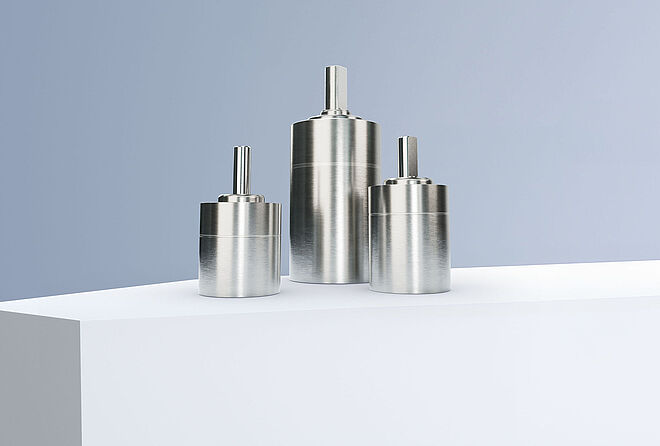 三台FAULHABER GPT系列行星齿轮减速机，排列在灰蓝色背景前的白色阶梯上。