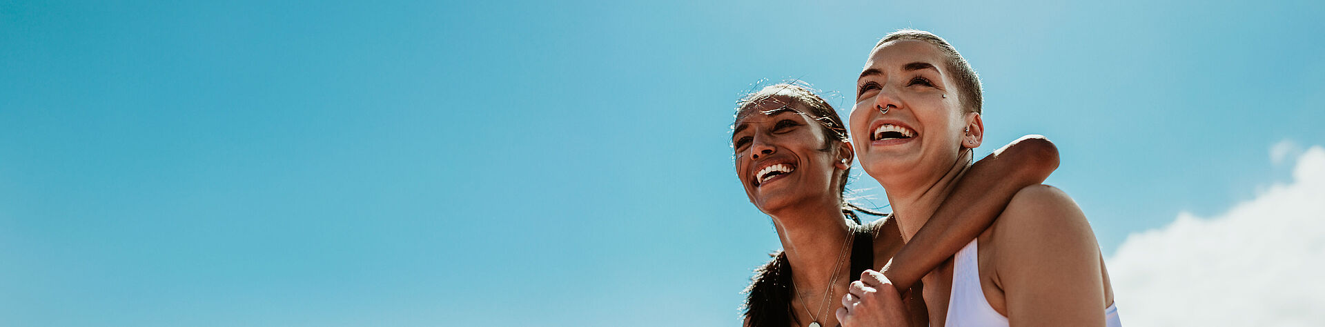 用于 Scaldopack 运动凝胶包装机的 FAULHABER 直线电机 蓝天白云下的两位女运动员。其中一人搂着另一人的肩膀。